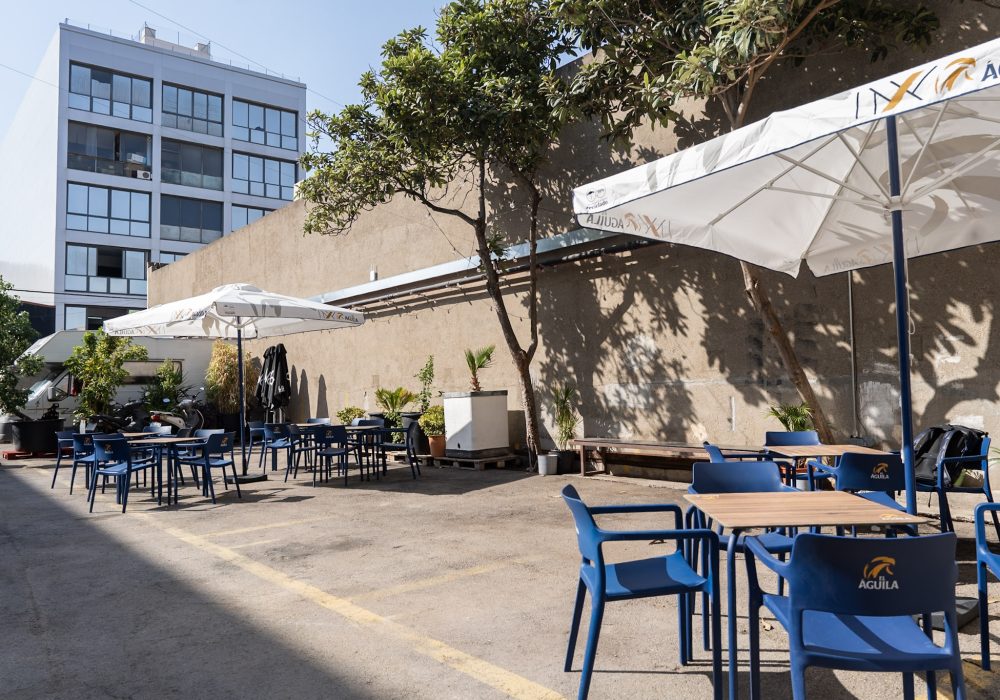 La Terraza: patio exterior con árboles, mesas y sombrillas